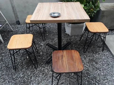 A café table and chairs with stone floors and plant decorations on the walls Фото