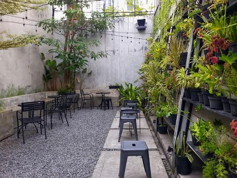 A café table and chairs with stone floors and plant decorations on the walls 스톡 사진