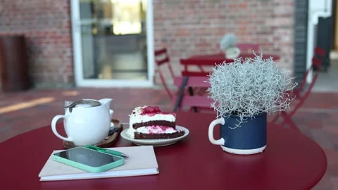 Cafe table with cake tea smartphone and notebook ready for a quiet break Stock Footage 345028817