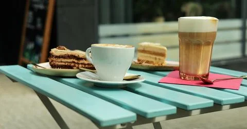 Cafe table features frothy latte and creamy cappuccino with gluten-free cakes Stock Photos