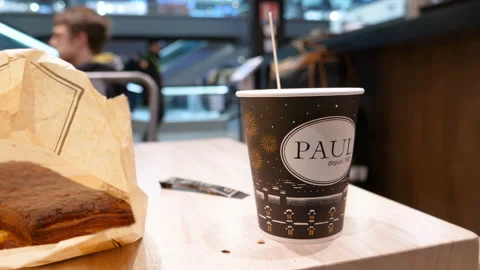 Cafe table with Paul paper cup - drinking coffee at one of the large bakery Stock Footage 167982295