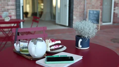 Cafe table with raspberry cake tea smartphone and notebook Stock Footage 345028773