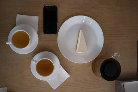 In a cafe on the table there is a phone cake teapot cups of tea napkins Stock Photos