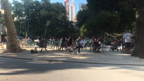 Cafe Tables in Madison Square Park Under Trees, Empire State Building Above Stock Footage 347910591