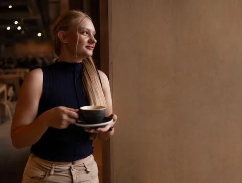 Cafe visitor drinks coffee alone. Beautiful blonde girl whiles away time Photos