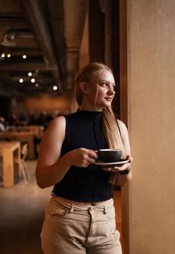 Cafe visitor drinks coffee alone. Beautiful blonde girl whiles away time Photos