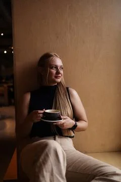 Cafe visitor drinks coffee alone. Beautiful blonde girl whiles away time Photos