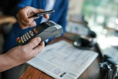 Cafe waiter using an nfc terminal with a customer's phone Stock Photos