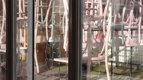 Cafe window with stacked chairs and string lights inside Stock Footage 335451792