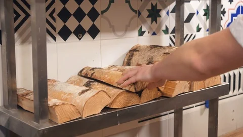 Cafe worker puts chopped wood logs on metal shelf closeup Stock Footage 127214915