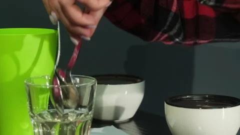 Cafe worker uses couple of spoons pouring coffee into plastic glass Stock Footage 306622080