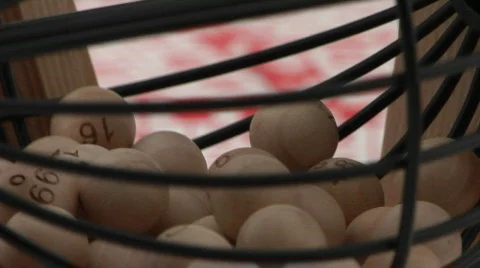 A cage of bingo balls spins in front of bingo cards. Stock Footage