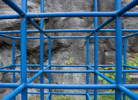 A cage structure for kids do play with, next to a rock wall Foto stock
