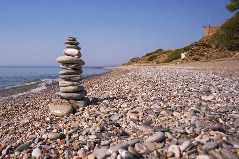 A cairn made out of flat rounded rocks erected on a sunny pebble beach near.. Foto stock
