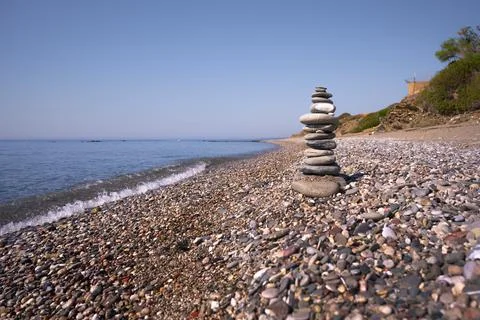 A cairn made out of flat rounded rocks erected on a sunny pebble beach near.. Foto stock