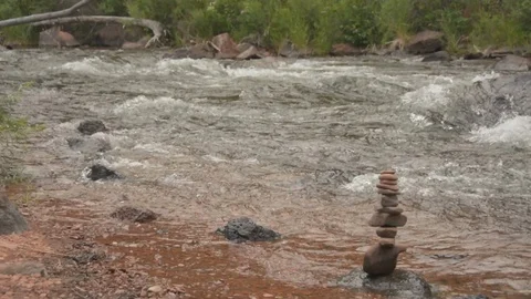 Cairn rock formation on the side of the river, water flows through. Stockbeeldmateriaal 95165257