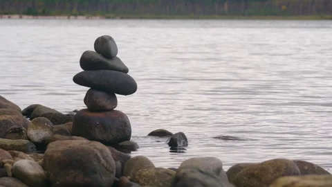 Cairn rock stack on lakeshore surrounded by autumn forest in 4K video from Karel Stock Footage 308959092