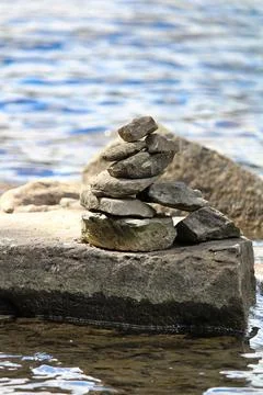 A cairn stack on a large flat rock near water Stock Photos