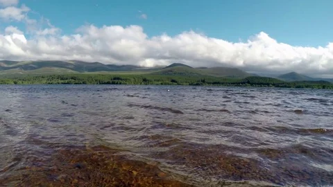 Cairngorm Aviemore Loch Morlich clear water waves with clouds hills background Stock Footage 78242589