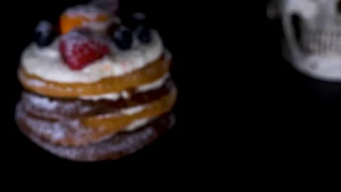 Cake and skull in a festive cap on a black background. 4k, dolly shot Видео 90163310