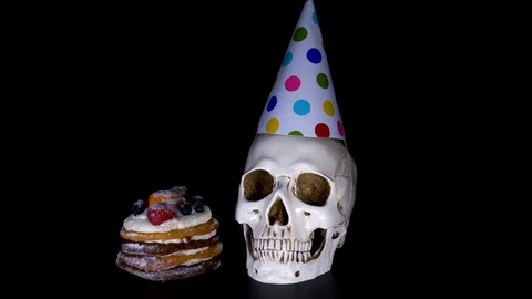 Cake and skull in a festive cap on a black background. candy, slow-motion Stock-Footage 90164056