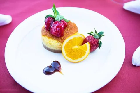 Cake-cheesecake decorated with strawberries and orange lies on a white pla... Stock Photos