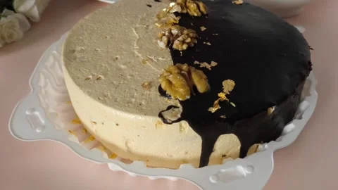 A cake with chocolate, nuts and cream on the table, next to a mug of tea, a Stock Footage 324782602