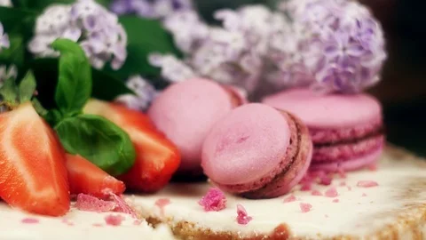 Cake with a cut out decorated with macaroons, sliced strawberries and lilac Video stock 99321159