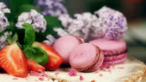 Cake with a cut out which decorated with macaroons, strawberries and lilac Stock Footage 98800423