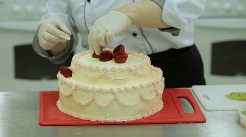 Cake decorating. Close up of baker hands decorate big cream cake with fruits Vidéo 50476316