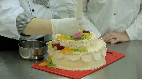 Cake decorating. Confectioner-baker decorates big cream cake with fruits Video stock 50476013