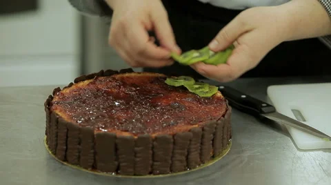 Cake decorating. Confectioner decorates beautiful cake with chocolate and kiwi Stock Footage 50476490