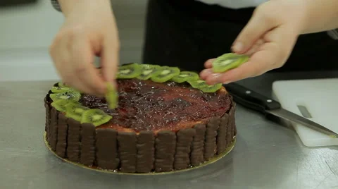 Cake decorating. Confectioner decorates beautiful cake with chocolate and kiwi Stock Footage 50476771