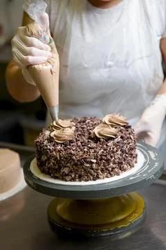 Cake decoration process in a busy kitchen setting 库存照片