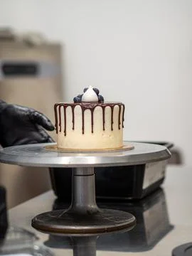 Cake designer decorating a chocolate drip cake with meringue and blueberries Stock Photos
