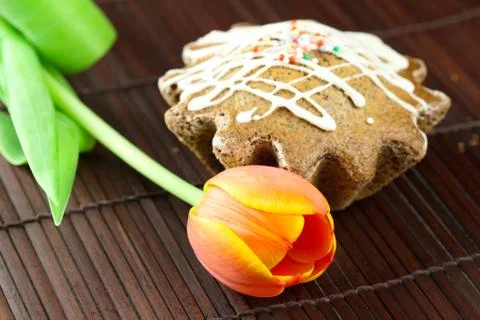 Cake with icing and a tulip lying on a bamboo mat Foto stock