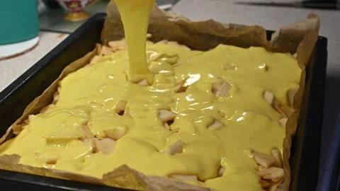 Cake making process with apples, cake batter covering sliced fruit evenly, Stock Footage 331840599