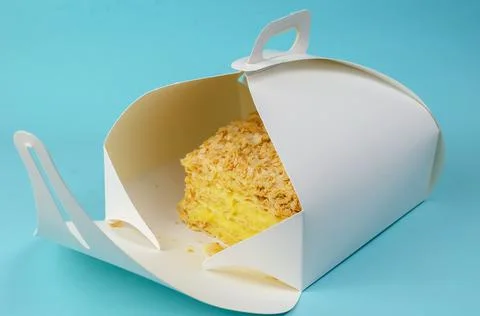 The cake is packaged in a white paper box on a light blue background. Open Kr Stock Photos