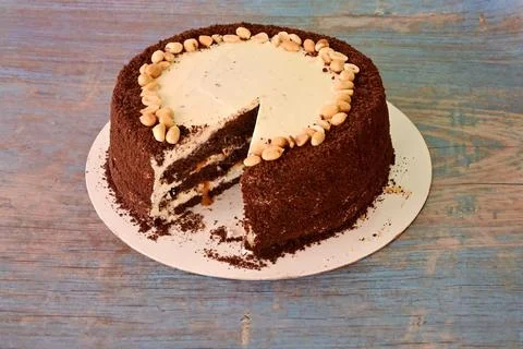 A cake with a piece missing and nuts on top Stock Photos