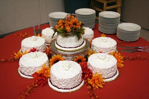 Cake place setting on round table with red table cloth and stacks of serving  Stock Photos