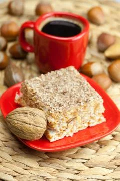 Cake on a plate, nuts and a cup of coffee on a wicker mat Stock Photos