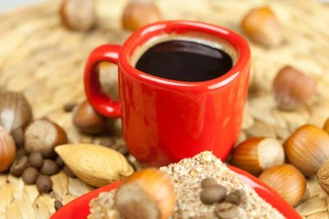 Cake on a plate, nuts and a cup of coffee on a wicker mat Stock Photos