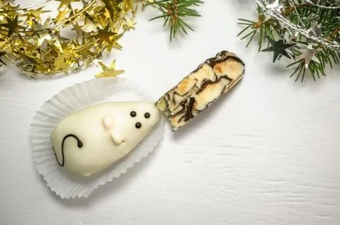 A cake in the shape of a white mouse that eats halva on the Christmas table. Stock Photos