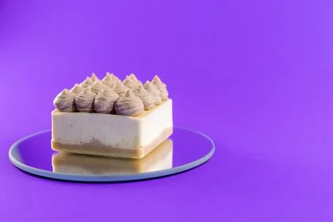 Cake sits on a round mirror against a bright purple background during a des.. Stock Photos