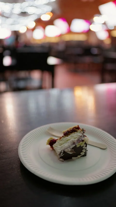 Cake slice on white plate with fork in softly blurred cafe interior and warm Vidéo 345265310