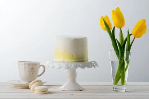 Cake on a stand, macaroni sweets, spring tulips and a vintage tea cup Stock Photos