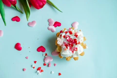 Cake with whipped cream and red tulips on a blue background, top view Stock Photos