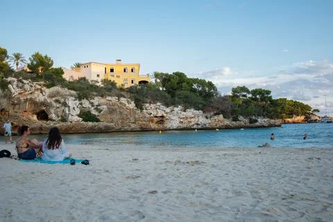 Cala Ferrera beach in the evening panoramic view. Tourists spending time by .. Stock Photos