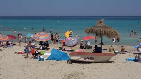Cala Millor Mallorca Spain: People playing on the beach next to a boat Video stock 81069001
