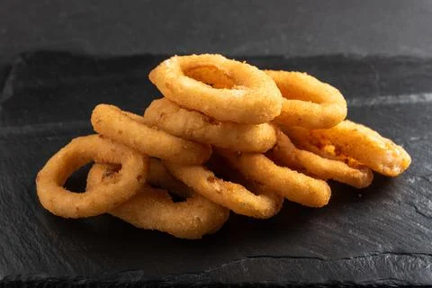 Calamari rings deep-fried in breading. Crispy squid rings on a dark background Stock Photos